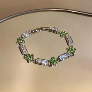 Detail of elegant silver bracelet featuring green flower clusters and rectangular zircons.