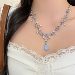 Close-up of blue floral rhinestone necklace with teardrop pendant worn on model