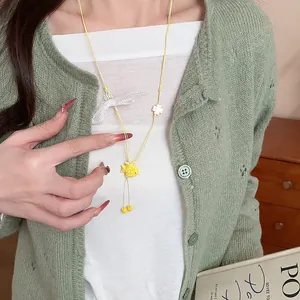 Close-up detail of a yellow ceramic fish pendant necklace on a leather cord worn by model