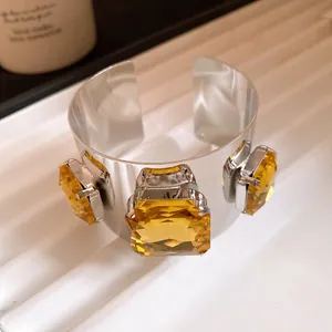 Close-up of a silver metal cuff bracelet featuring square amber-colored crystals