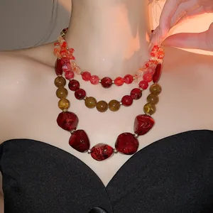 Détail d'un collier à perles multicouche en résine acrylique rouge et ambre vintage