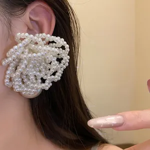 Detailed close-up of elegant large multi-layer pearl flower earring shown on a model