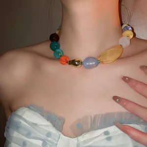 Gros plan détaillé d'un collier de perles en résine acrylique coloré sur un modèle.