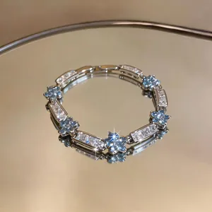Sparkling silver flower bracelet with blue zirconia stones shown on a mirror surface