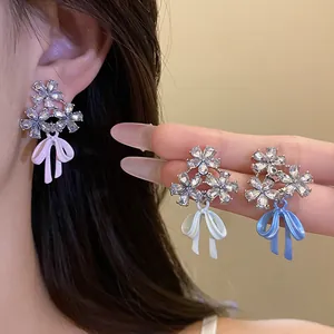 Detail of crystal flower and bow earrings in pink, white, and blue finishes