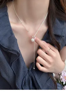 Close-up of elegant silver necklace with zircon flower cluster and pearl tassel.