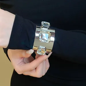 Close-up detail of a silver cuff bracelet featuring three large square crystals on a wrist.
