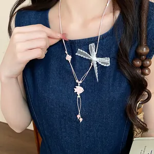 Close-up detail of a sweet pink ceramic fish necklace with a white lace bow style