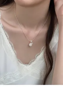Detailed macro view of an elegant zircon flower cluster pearl necklace on a model's neck.