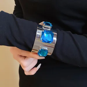 Close-up of a wide silver cuff bracelet with three large square blue crystals