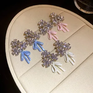 Detailed view of zircon flower cluster earrings with delicate enamel bow charms