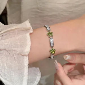 Detail of a delicate silver bracelet with green zircon flowers and crystal links