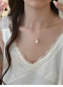 Detailed close-up of an elegant pearl cluster and zircon necklace worn by a model