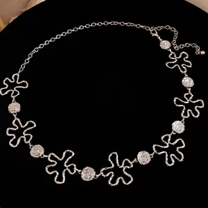 Détail d'une chaîne de taille en métal argenté avec un design de fleurs et roses évidées