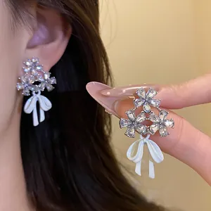 Close-up of elegant flower and white bow earrings with sparkling zircon detail