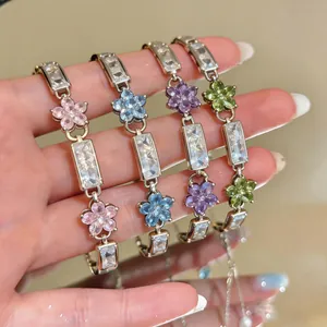 Detail view showing colorful zircon flower bracelets in pink, blue, purple, and green finishes