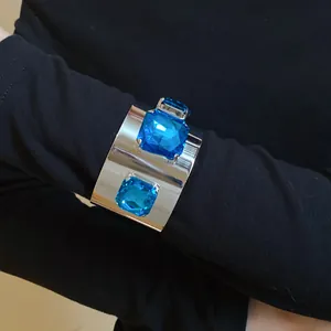 Detailed view of silver cuff bracelet with square blue crystals on black sleeve