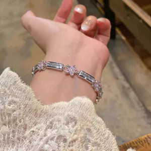 Detailed view of silver-toned flower bracelet with pink and clear zircons on wrist