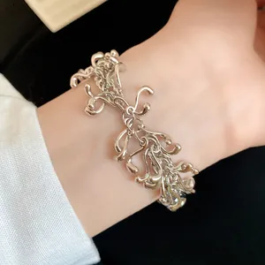 Close-up detail of a silver irregular geometric fluid bracelet worn on a female wrist