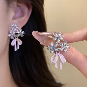Close-up detail of sparkling zircon flower earrings with elegant pink enamel ribbon bows