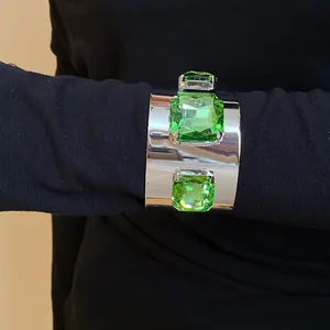 Detailed view of a wide silver cuff bracelet with three large square green crystals