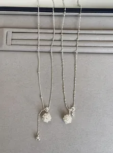 Detailed macro view of silver zircon flower cluster and pearl necklaces on grey velvet display