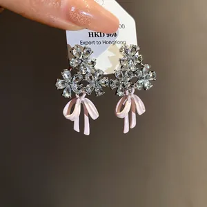 Detailed close-up view of zircon flower and pink enamel bow stud earrings for women