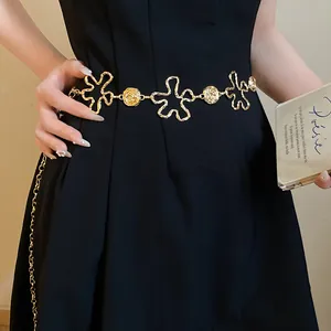 Vue détaillée d'une chaîne de taille en métal doré aux fleurs ajourées sur une robe noire.