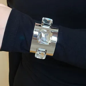 Close-up of a silver-toned metal cuff bracelet featuring three large square crystals.