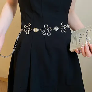 Gros plan d'une chaîne de taille vintage en métal argenté à fleurs évidées sur robe noire