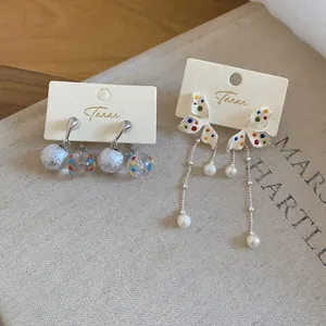 Dettaglio degli orecchini a fiore a pois colorati con lunghe nappe di perle eleganti