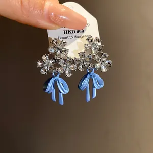 Detailed view of silver needle enamel flower and blue bow zircon stud earrings