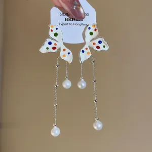 Eleganti orecchini a farfalla in argento con pois colorati e perle bianche raffinate.