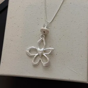 Dettaglio del ciondolo a forma di fiore traforato in argento con cuore centrale