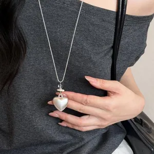 Primo piano dell'elegante collana con ciondolo a cuore argento su top grigio