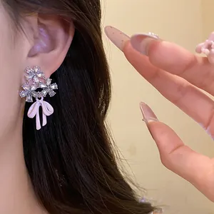Detailed macro shot of elegant zircon flower earrings featuring a dainty pink enamel bow design
