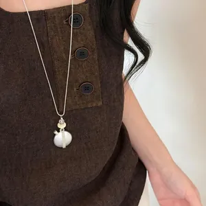 Collana con pendente argento e nappa su top marrone testurizzato.
