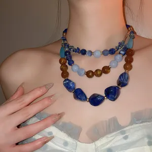 Gros plan d'un collier bohème à plusieurs rangs en perles de résine acrylique bleues et ambre