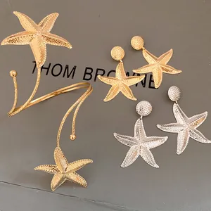 Macro view showing the textured gold and silver starfish earrings and matching bangle
