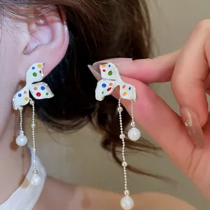 Primo piano di orecchini a fiore con pois colorati e nappe di perle eleganti da donna.