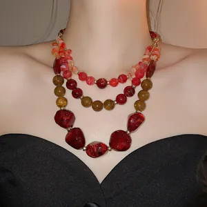 Détail d'un collier bohème multi-rangs en résine acrylique avec perles rouges et ambre