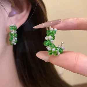Detail view of stylish C-shaped hoop earrings featuring green glass beads and white pearls
