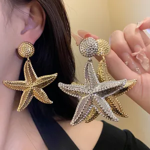 Close-up of vintage metallic starfish drop earrings with textured gold and silver finish.