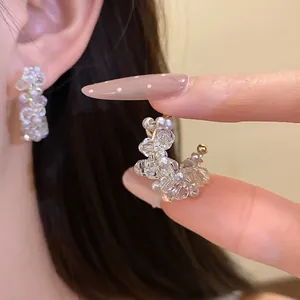 Detailed macro view of elegant C-shaped earrings featuring clear glass beads and pearls