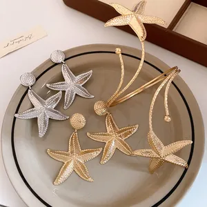 Detailed view of gold and silver starfish earrings with hammered metal texture on plate