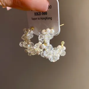 Detailed view of beaded C-shaped earrings featuring pearls and glass beads on a product tag
