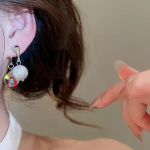 Primo piano di orecchini coreani con pois colorati indossati da una modella elegante.