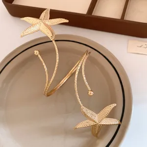 Detailed view of luxury gold starfish statement wrap earrings on a minimalist plate