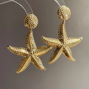 Macro detail of elegant gold-toned starfish dangle earrings with rich textured finish