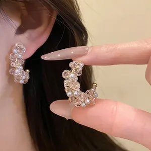 Close-up of elegant C-shaped earrings crafted with sparkling glass beads and pearls